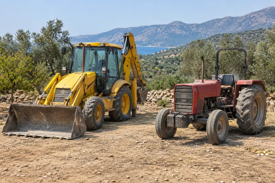 Şantiyede iş makinesi ve tarlada traktör